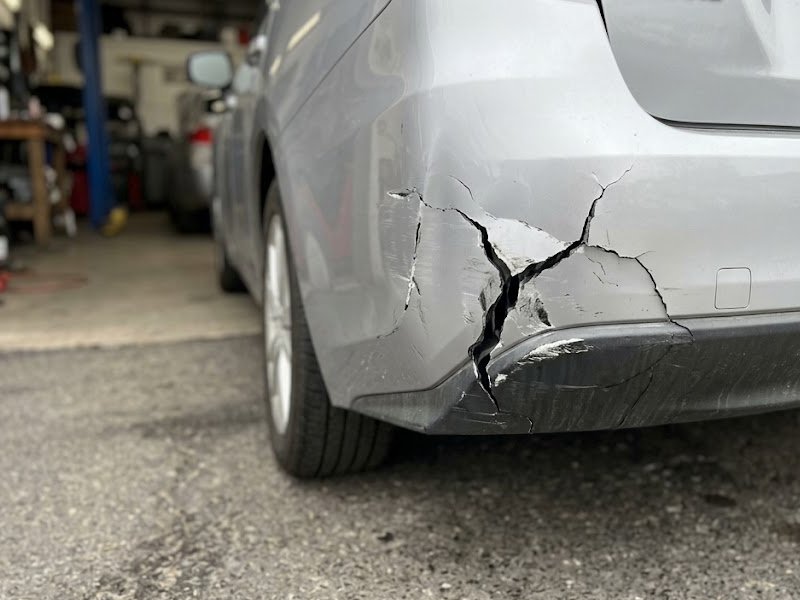 Split rear bumper corner on a car outside a repair shop